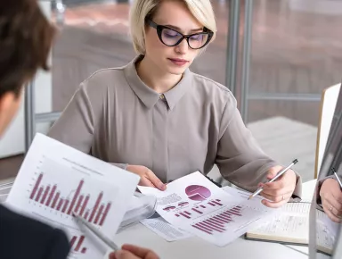 Directrice financièreanalysant un rapport de statistiques en regardant des graphiques de données financières lors d'une réunion avec des collègues 