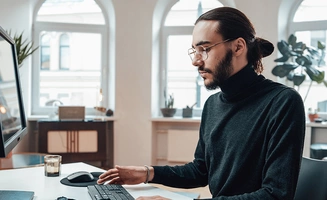 Un chargé d'études média devant un ordinateur au bureau