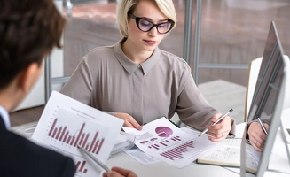 Directrice financièreanalysant un rapport de statistiques en regardant des graphiques de données financières lors d'une réunion avec des collègues 