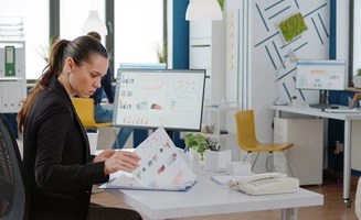 Femme d'affaires travaillant avec des ordinateurs et des graphiques de données sur papier